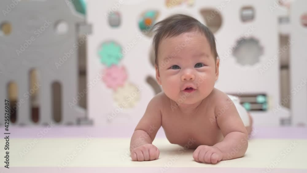 3 months. cute asian baby infant playing on pastel play mat. lovely kid learning to crawl at home. soft mat in playpen protection in baby playground and plastic fence. 3 months. cute asian baby infant playing on pastel play mat. lovely kid learning to crawl at home. soft mat in playpen protection in baby playground and plastic fence.