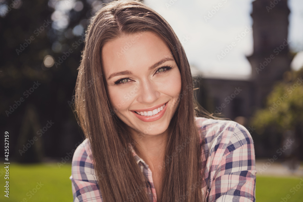 Close-up photo portrait of girl smiling cheerful wearing checkered shirt sitting outside in sunny weather Close-up photo portrait of girl smiling cheerful wearing checkered shirt sitting outside in sunny weather
