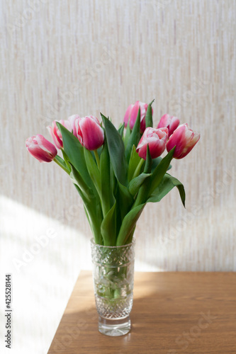 Few pink tulips in crystal vase on table