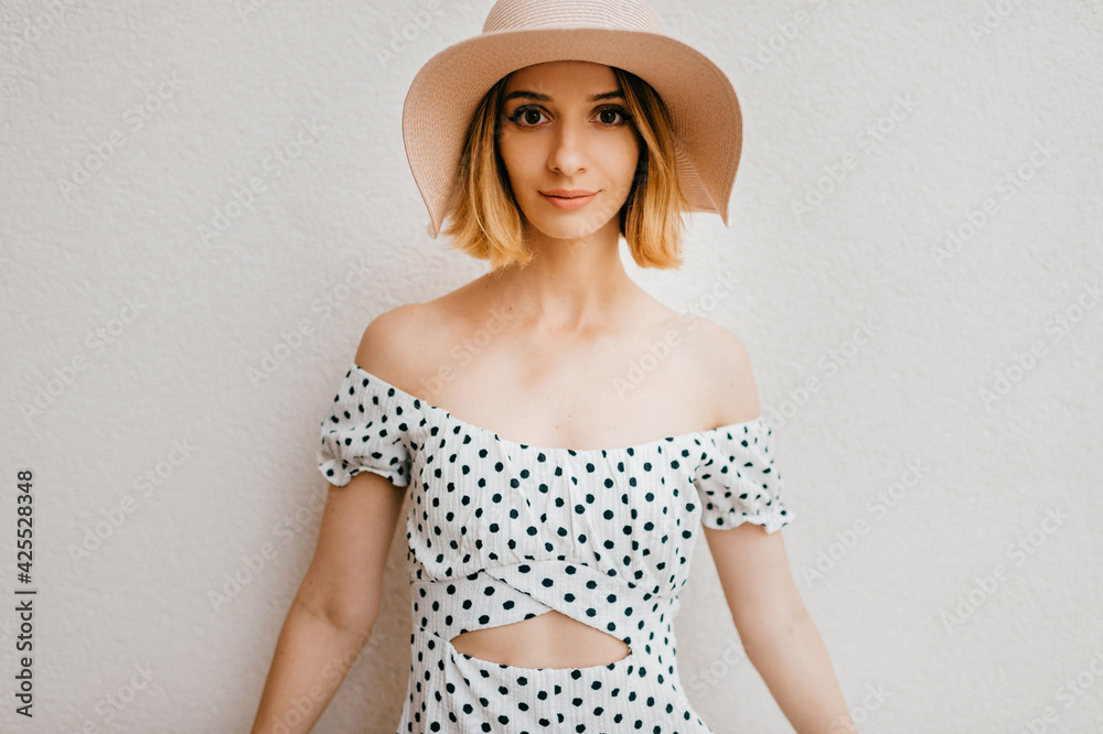 Portrait of elegant stylish blonde short hair girl in hat and dress posing over white background