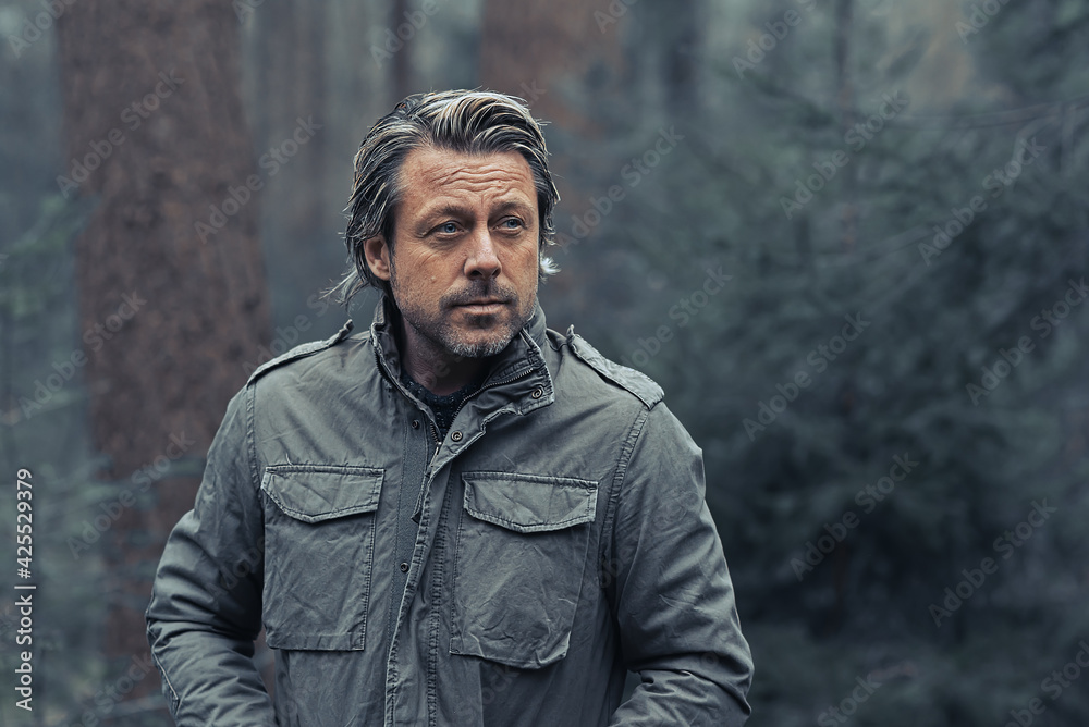 Blonde man in green coat walks in a pine forest. Blonde man in green coat walks in a pine forest.