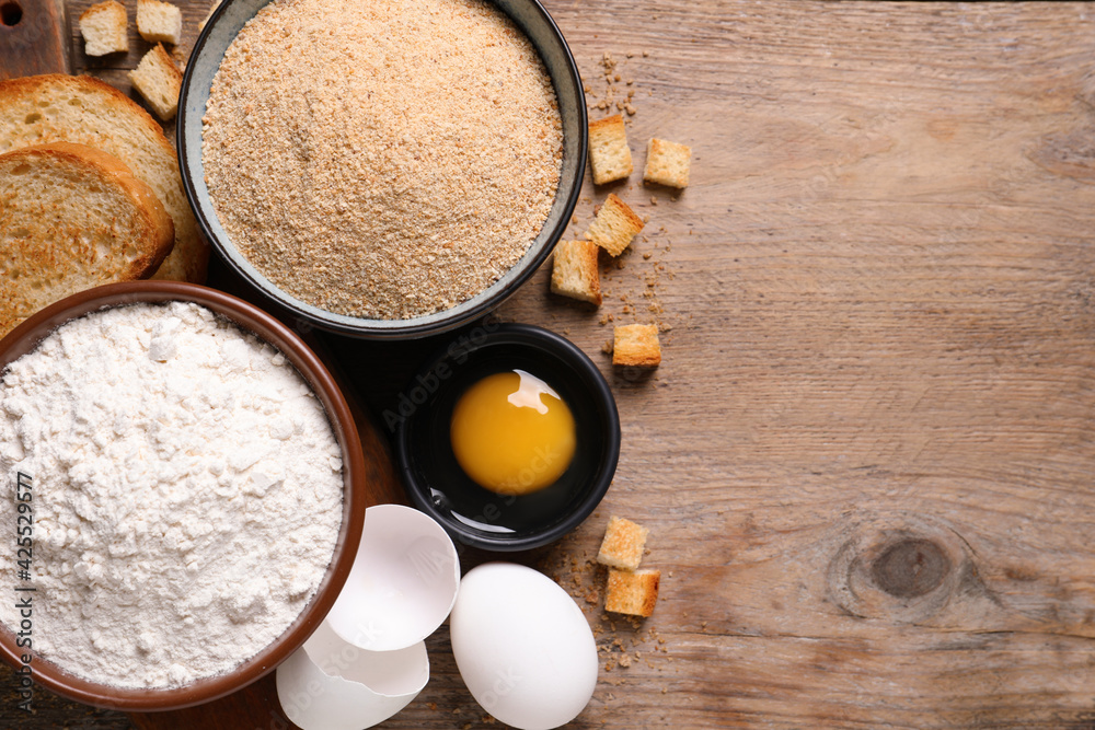 Fresh breadcrumbs, flour and eggs on wooden table, flat lay. Space for text Fresh breadcrumbs, flour and eggs on wooden table, flat lay. Space for text