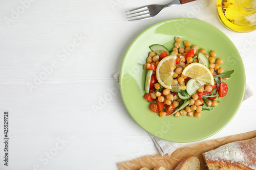 Delicious fresh chickpea salad served on white wooden table, flat lay. Space for text