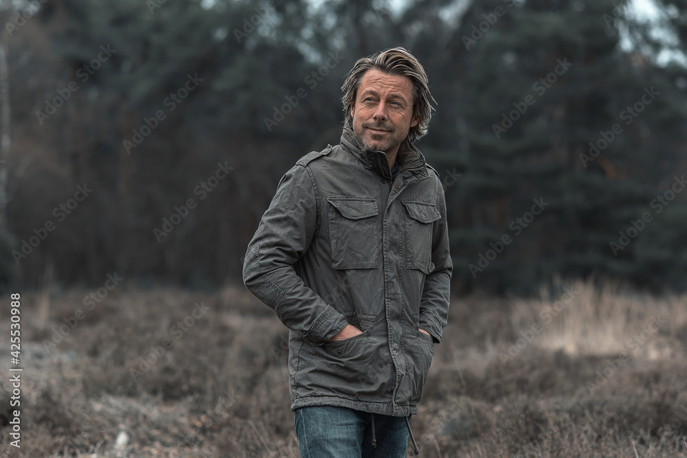 Smiling blond man in green coat on heathland in nature reserve. Smiling blond man in green coat on heathland in nature reserve.
