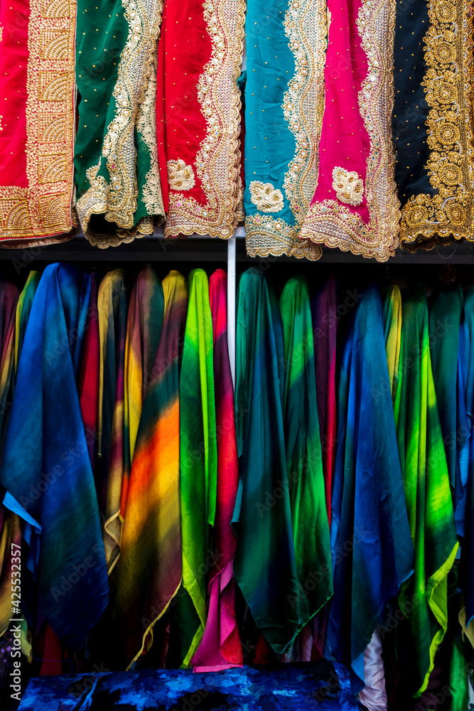 Rolls of fabric and textiles for sale stacked on shelves in shop,View of cloth rolls of different colors and patterns on shelves in fabric store, Colorful traditional indian, turkey costumes
