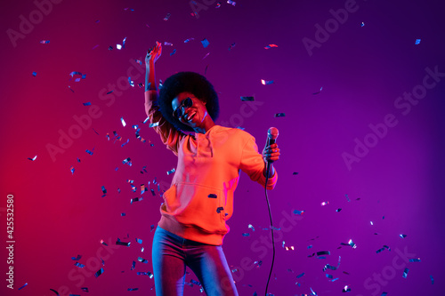 Photo of adorable pretty dark skin woman wear sweatshirt singing microphone dancing isolated gradient background