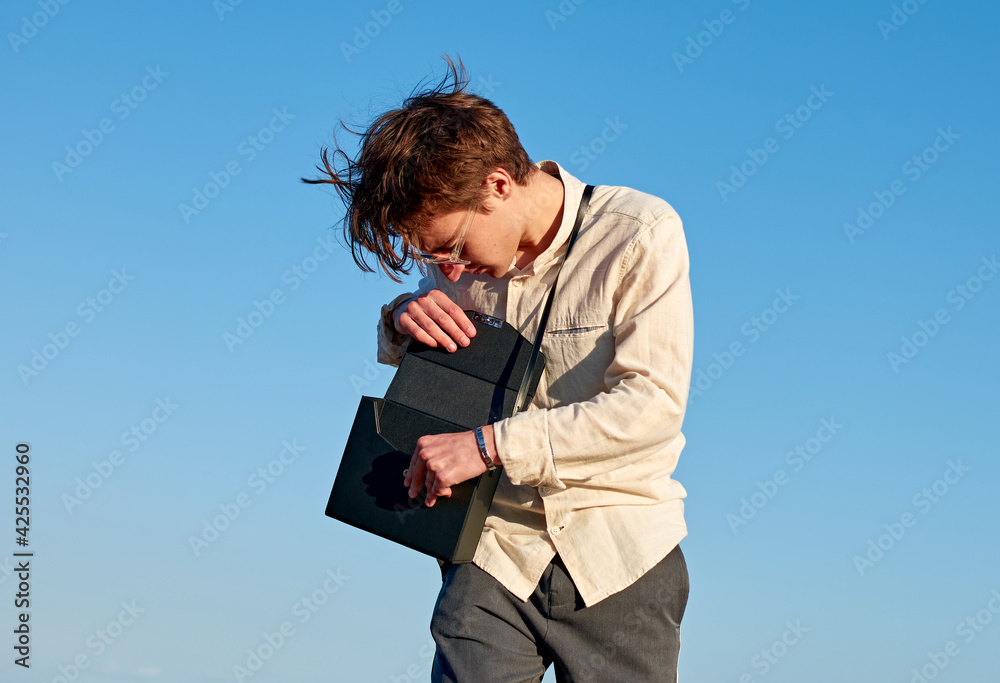 A Caucasian man from Spain standing and opening his black handbag on clear sky background A Caucasian man from Spain standing and opening his black handbag on clear sky background