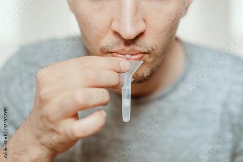 Lateral-Flow-Test covid rapid home-use test kit for saliva - step 1 - spit with mouth through funnel in plastic tube to collect sample - No more swabs in the throat or nose: just spit in a tube! photo