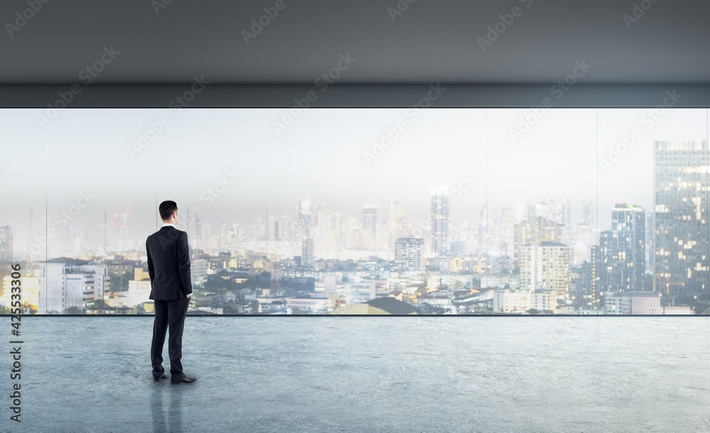 Future vision concept with businessman looking through transparent wall in empty hall room with glossy floor and night city view. Mock up Future vision concept with businessman looking through transparent wall in empty hall room with glossy floor and night city view. Mock up