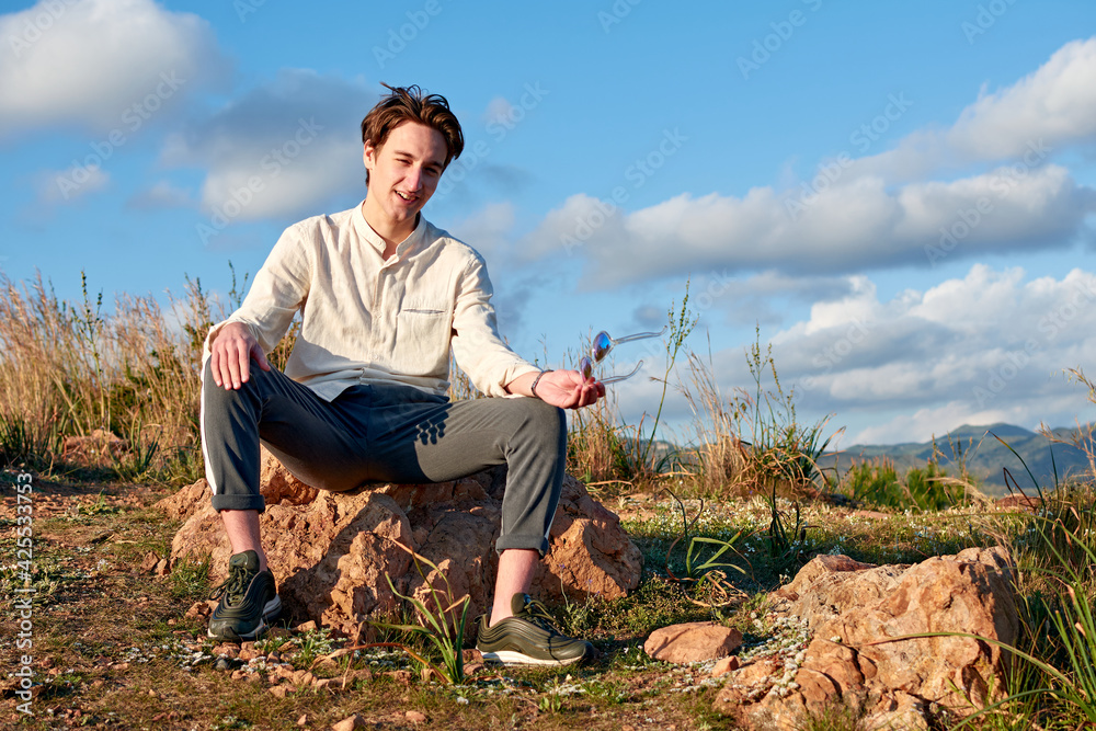 A Caucasian man from Spain sitting on a rock in a mountainous and cloudy area