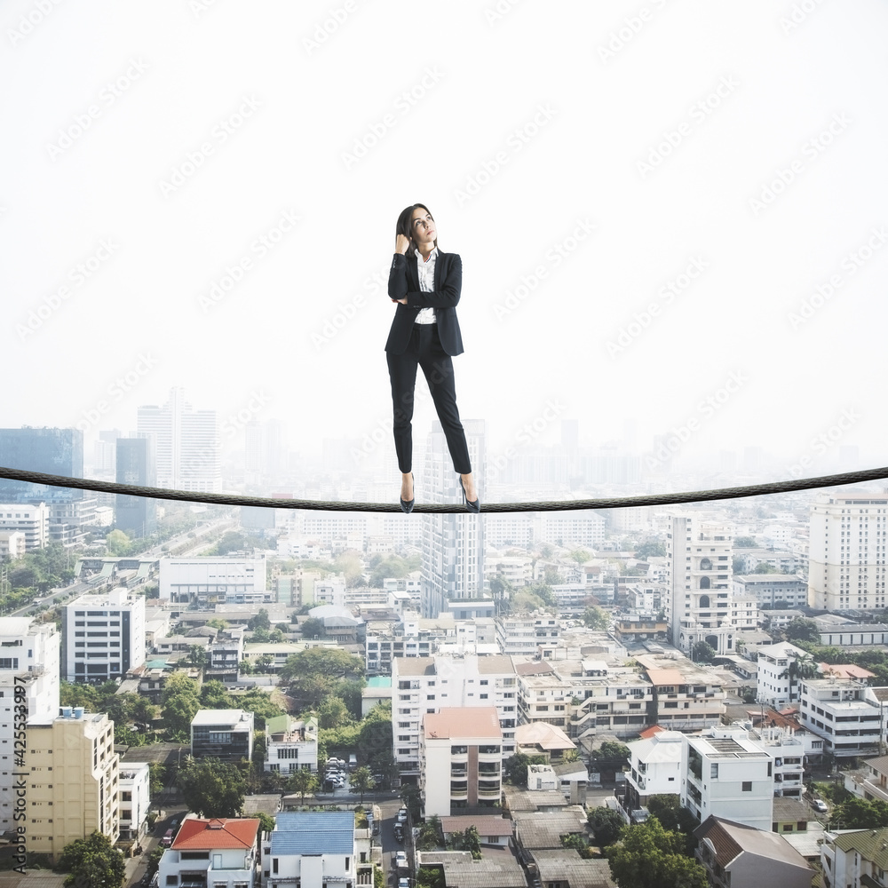 Professional strategy concept with businesswoman standing confidently on a tightrope above city Professional strategy concept with businesswoman standing confidently on a tightrope above city