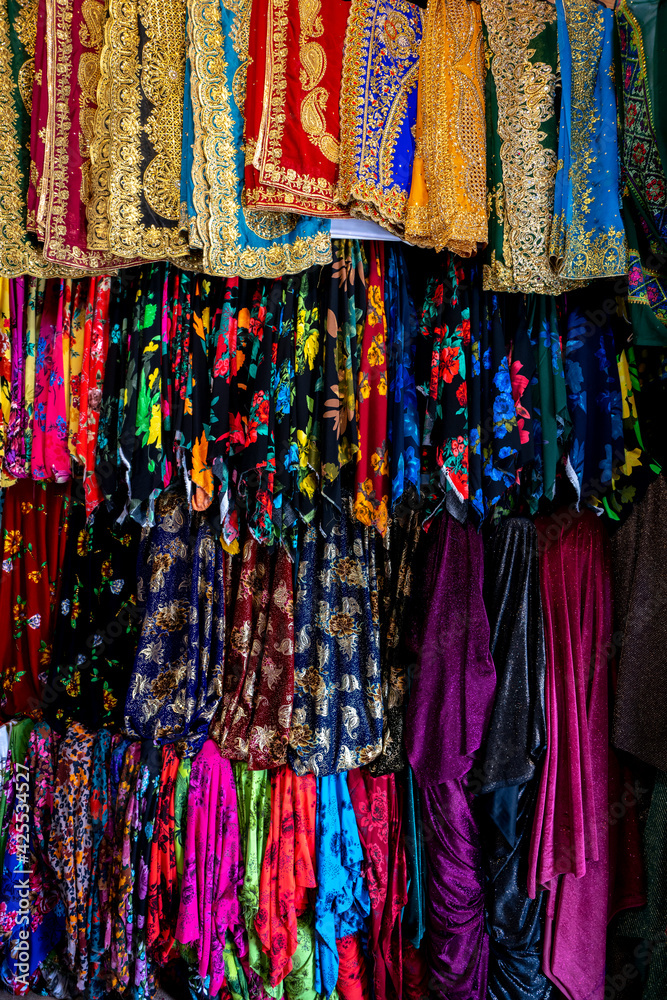 Clothes in shop, Rolls of fabric and textiles for sale stacked on shelves in shop, View of cloth rolls of different colors and patterns on shelves in fabric store.