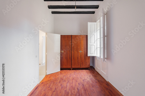 Photography White room interior with wooden wardrobe, black beams, window and boot marks on the parquet