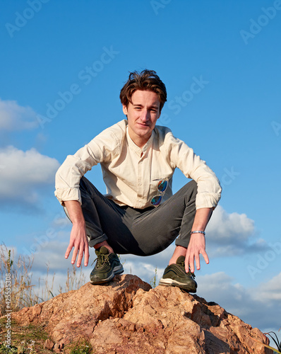 Obraz na plátně A Caucasian man from Spain squatting on a rock surrounded by grass