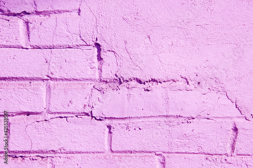 Texture of a brick wall partially covered with plasterwork and painted in pink color