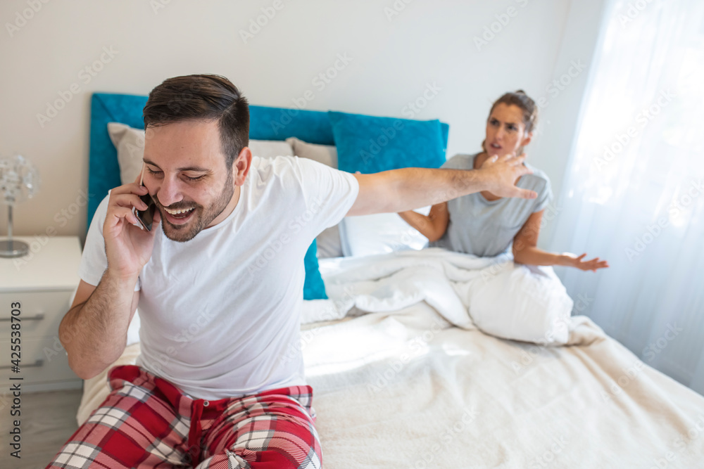 Obraz premium Smartphone obsession causing problems in marriages. Young woman is feeling depressed while her boyfriend is text messaging on cell phone with some other woman