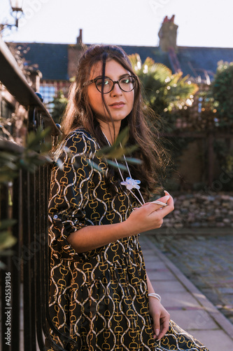 Stylish brunette woman with glasses. Decorations. Old town street background.