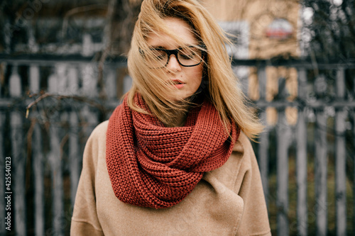 Portrait of young elegant blond girl with wind blown hair posing outdoors