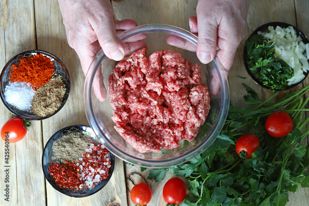 Minced meat in a bowl and the hands of the cook. Cooking minced meat for burgers or grilling. Minced meat in a bowl and the hands of the cook. Cooking minced meat for burgers or grilling.
