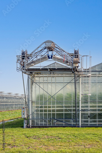Greenhouse deck cleaner on the roof of a Dutch greenhouse. A clean roof gives a higher light output and saves energy. The photo was taken on a sunny day in the beginning of spring.
