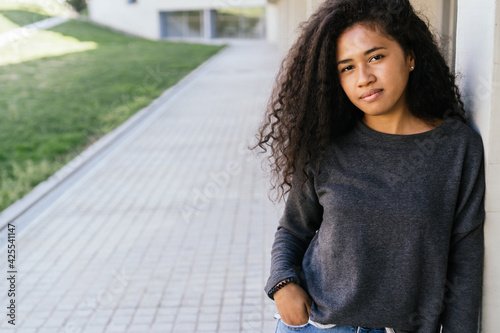 Young black girl with white smile and curly hair, copy space. Portrait of an afro girl with long hair. Horizontal photograph