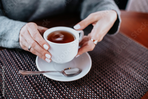 Drink Tea relax cosy photo with blurred background. Female hands holding mug of hot Tea in morning