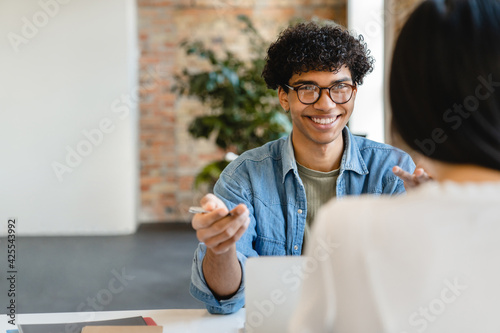Photos Successful young colleagues having negotiation at the working desk in office