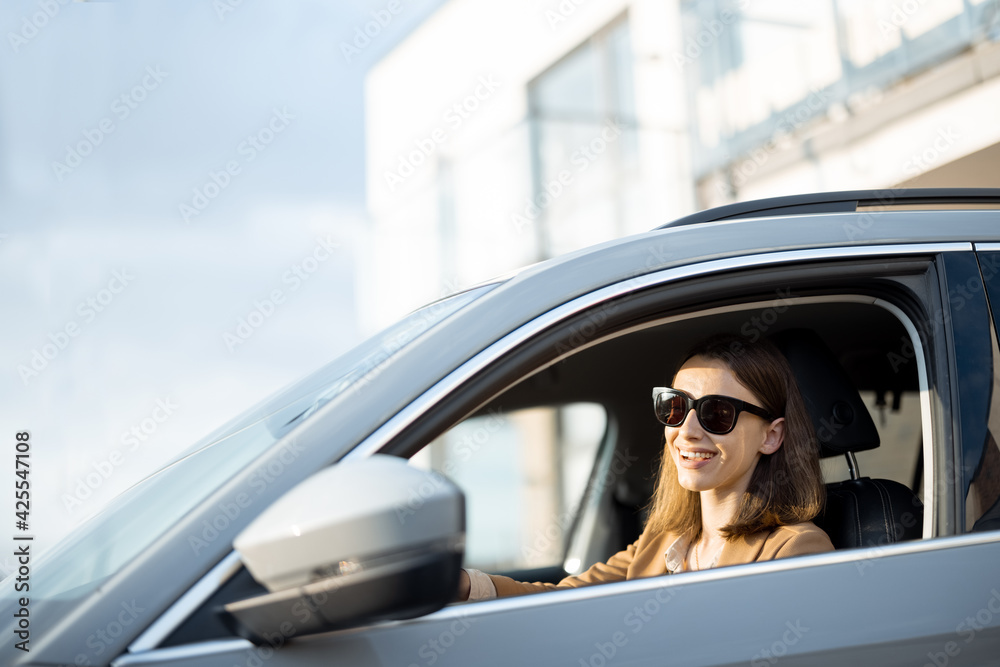 Naklejka premium Young woman in sunglasses left the house and driving a car. Businesswoman going to work from the house.