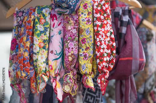 Floral woman scarves on a rack in outdoor sales.
