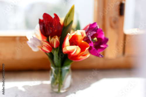 A bunch of tulips on the window. Still life with colorful tulip flowers bouquet on window sill