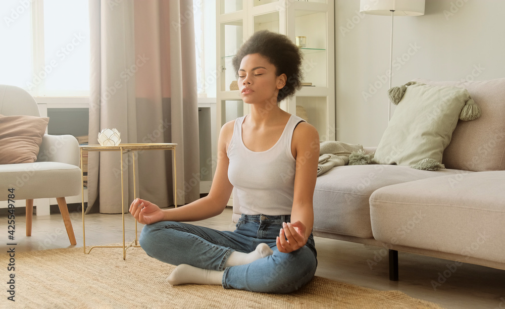 African american woman practice meditating and sitting at home. Calm female taking deep breath and relaxing with eyes closed. No stress and peace of mind. African american woman practice meditating and sitting at home. Calm female taking deep breath and relaxing with eyes closed. No stress and peace of mind.