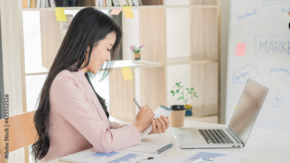 A beautiful Asian businesswoman works with documents, graphs, analyzes, and uses a laptop to work from home to create a social distance. A beautiful Asian businesswoman works with documents, graphs, analyzes, and uses a laptop to work from home to create a social distance.
