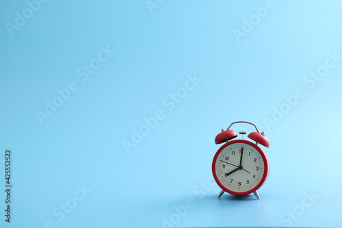 Red retro alarm clock isolated on a blue background
