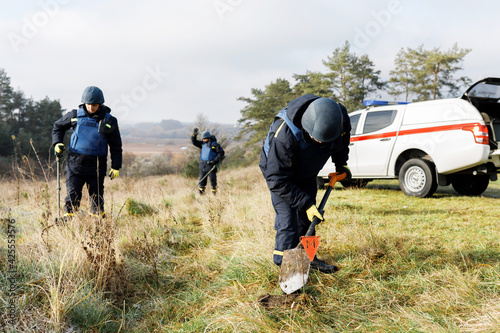 Men work in emergencies. Emergency workers work outdoors. A man in uniform works with a metal detector