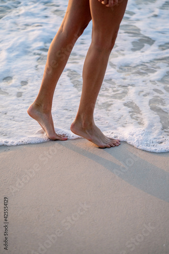 Female legs while walking on the beach by the water