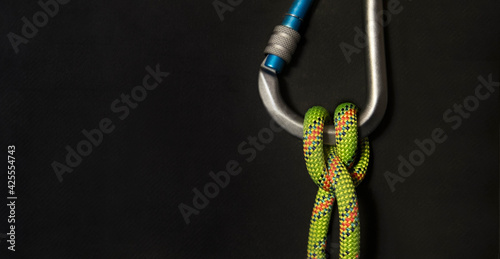 Carabiner with boatman's knot and fluorescent green rope on a black background.