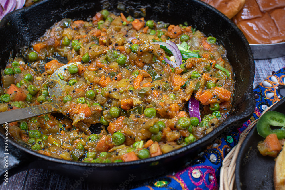 Indian pav bhaji served in cast iron dishes on wooden table
