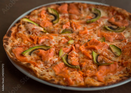 Pizza with salmon and avocado close-up