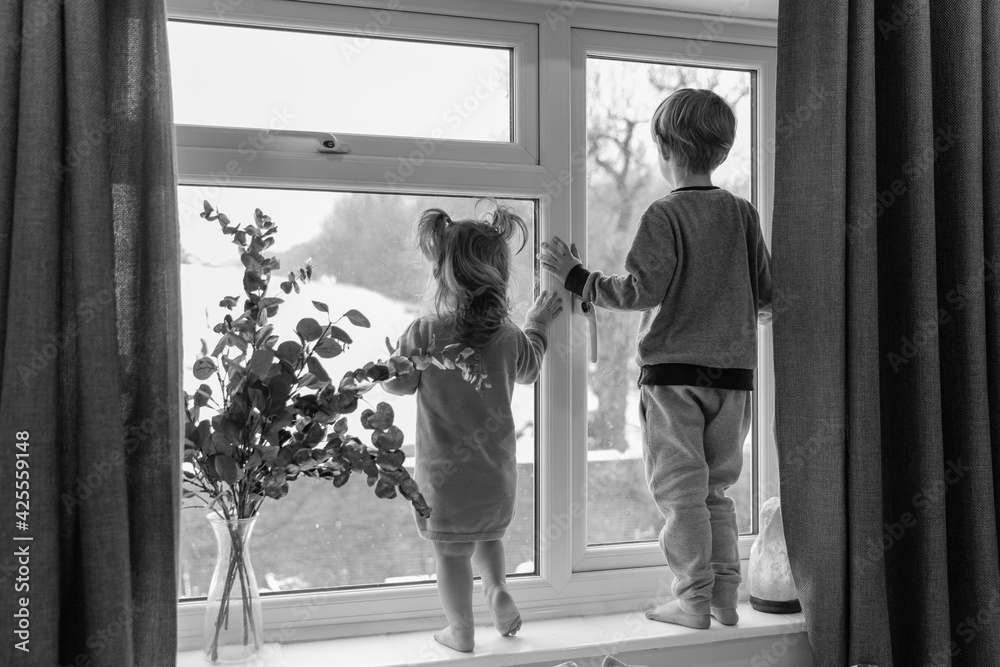 Happy children standing on the windowsill, looking through the window. Little girl and boy. Black and White. Happy children standing on the windowsill, looking through the window. Little girl and boy. Black and White.