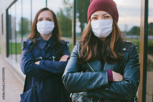 Close-up portrait of a girl with a medical mask on the background of another girl.