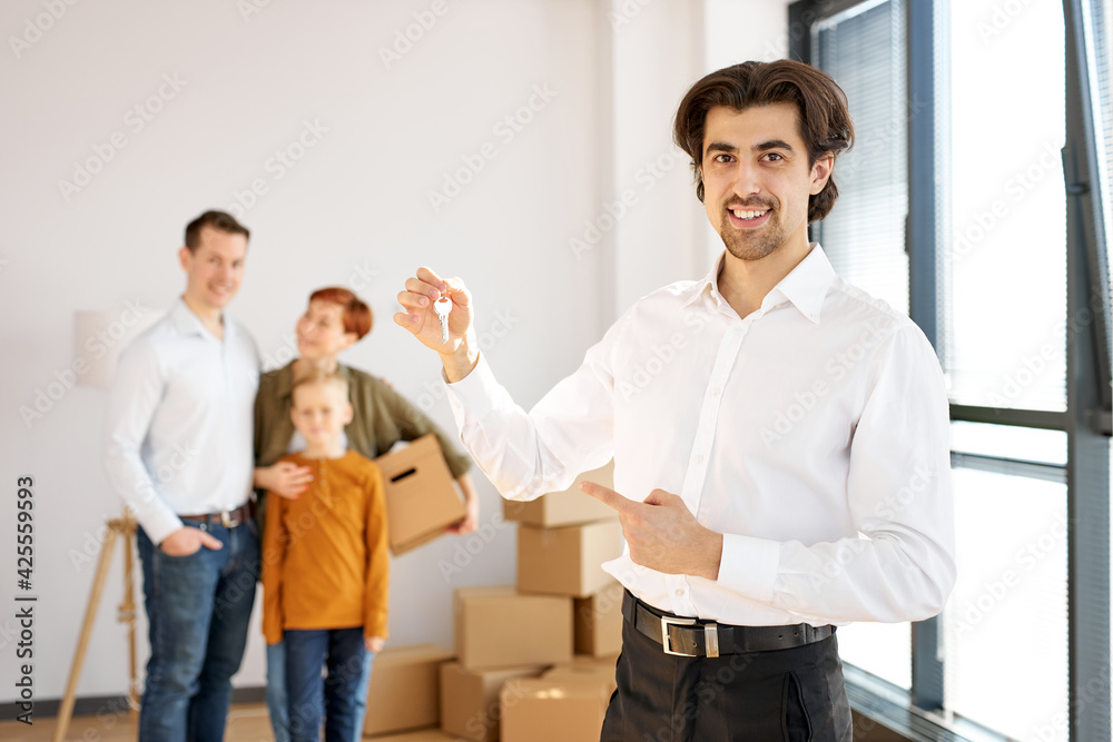 Handsome Smiling Cheerful Real Estate Agent In Formal Wear Holding Keys In Hands Posing At Camera Handsome Smiling Cheerful Real Estate Agent In Formal Wear Holding Keys In Hands Posing At Camera