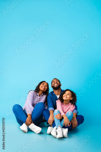 Smiling black family looking up at free copy space