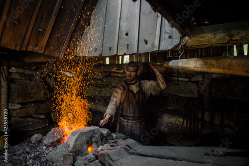 blacksmith at the stove. A man with a dirty face burns iron at the furnace 