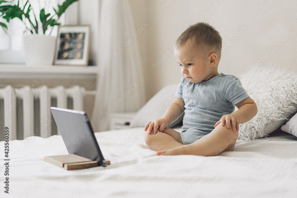 Little Boy sitting with a tablet in the room. The boy watching cartoons on the tablet. Technology concept. Little Boy sitting with a tablet in the room. The boy watching cartoons on the tablet. Technology concept.