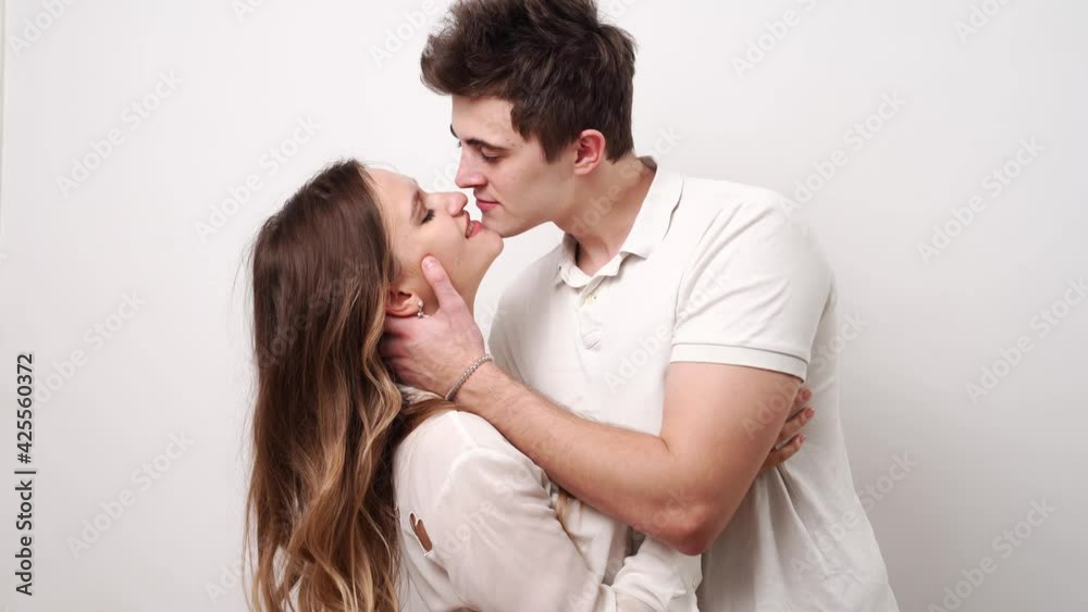 love, passionate and beautiful couple kisses against the white wall. love, passionate and beautiful couple kisses against the white wall.