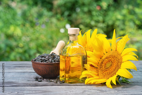 Sunflower seeds and flowers with bottle of oil on wooden table