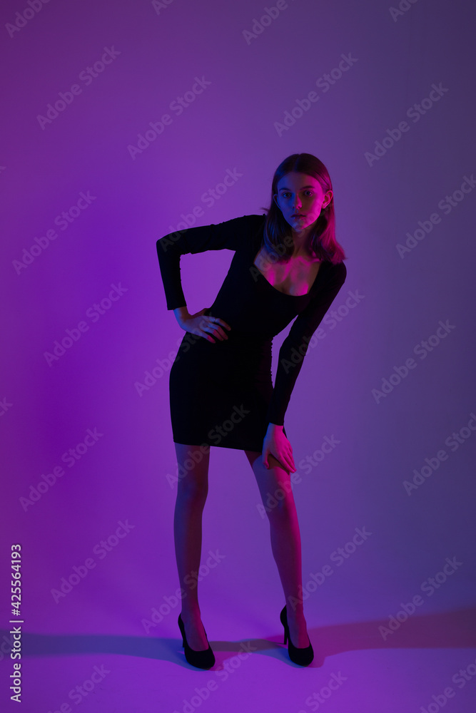 Girl portrait in neon light. Young slim woman model in black dress Girl portrait in neon light. Young slim woman model in black dress