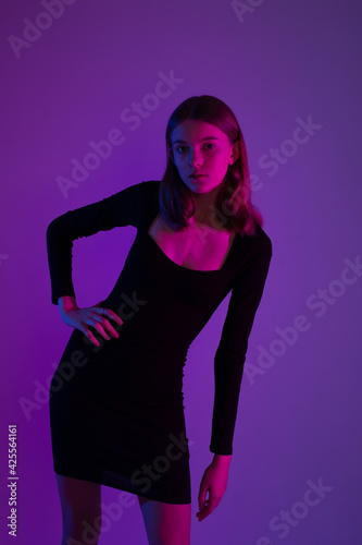Girl portrait in neon light. Young slim woman model in black dress © Andreshkova Nastya
