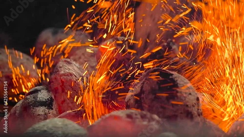 Grilled charcoal briquettes. The poker shifts the briquettes to the side. The layout of the coals: indirect method. Slow motion.