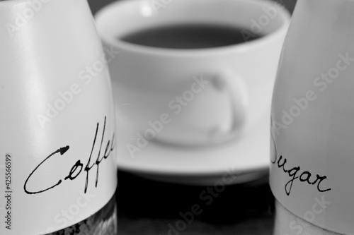 Black and white photo of coffee mug and coffee and sugar holders